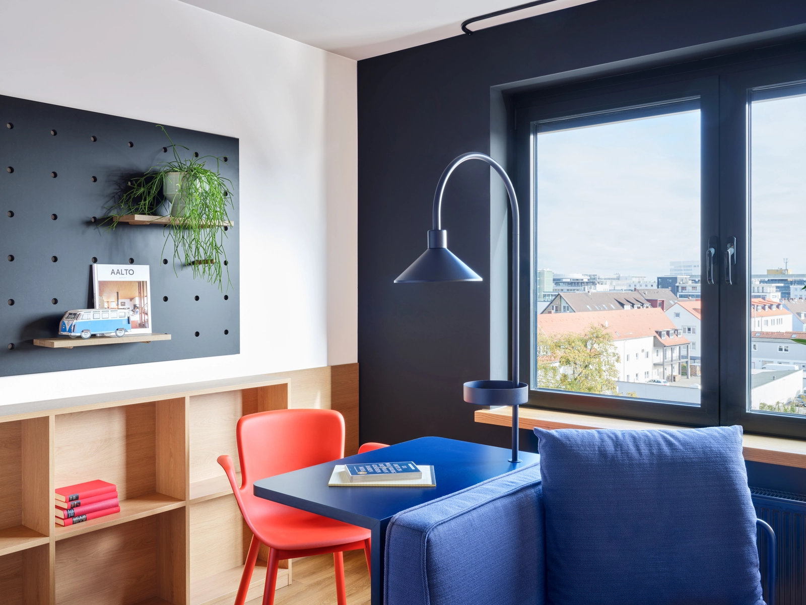 Kontrastreiches Apartment mit blauen und roten Akzenten in der Stayery Wolfsburg mit gemütlichen Sitzgelegenheiten